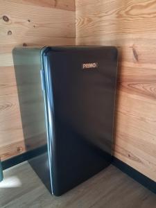 a black refrigerator sitting next to a wooden wall at Nanouchka in Médis