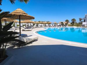 a swimming pool with chairs and umbrellas at Kos Palace in Tigaki