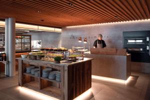 a man is standing in a kitchen with a buffet at Falkensteiner Hotel Kronplatz - The Leading Hotels of the World in Brunico