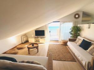 a living room with a white couch and a tv at Exclusive Beachfront Penthouse in Almayate Alto