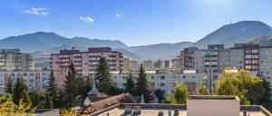 a city with buildings and mountains in the background at KOA - Aparthotel in Braşov