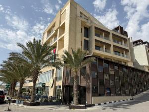 a building with palm trees in front of it at Lijam Hotel in Amman