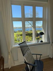a chair sitting in front of a large window at Bondegård med havudsigt in Kolding