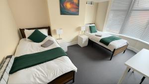 a bedroom with two beds and a desk and window at Stirling Steet in Wallasey
