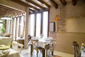 a restaurant with white tables and chairs and windows at Hotel Rural Doña Berenguela in Bolaños de Calatrava