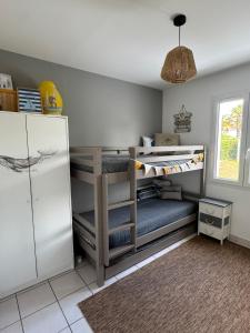 a room with three bunk beds and a refrigerator at La Fleur des Marais - Maison tout confort au calme, grand jardin & balançoire in Le Château-dʼOléron