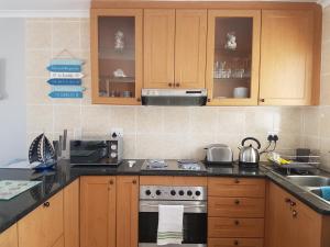 a kitchen with wooden cabinets and a stove top oven at Sea Gem in Big Bay