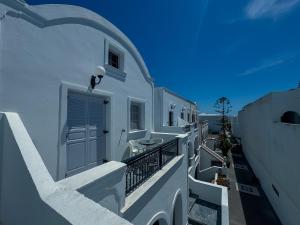 a white building with a door and a balcony at Tritonas Rooms in Kamari