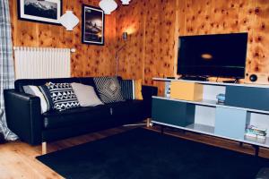a living room with a black couch and a flat screen tv at La Moussiere in Morgins +21 photos