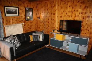 a living room with a black couch and a flat screen tv at La Moussiere in Morgins