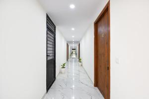 a hallway with white walls and a wooden door at FabHotel Evegreen, Faridabaad in Faridabad