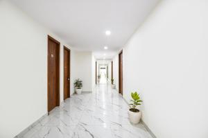 a corridor with potted plants in a white hallway at FabHotel Evegreen, Faridabaad in Faridabad