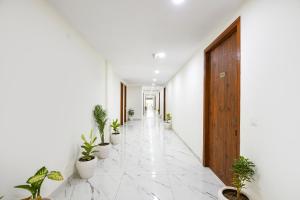 a hallway with potted plants and a wooden door at FabHotel Evegreen, Faridabaad in Faridabad
