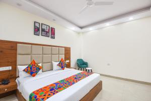 a bedroom with a large bed and a green chair at FabHotel Evegreen, Faridabaad in Faridabad +27 photos