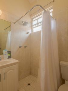 a bathroom with a shower with a white shower curtain at Lunar Apartments in Saint Michael +3 photos