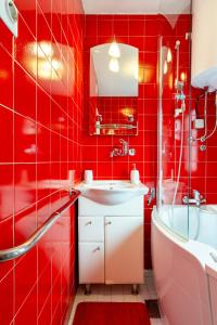a red tiled bathroom with a sink and a bath tub at Apartma v ograji in Šentjernej