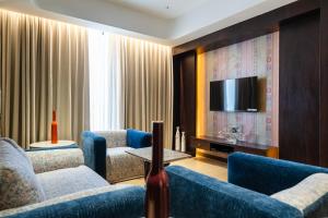 a living room with blue chairs and a tv at Akaya Elegance in Ahmadnagar