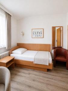 a bedroom with a bed and a chair at Pension Haus Weierts in Norderney