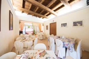 a dining room with white tables and white chairs at Locanda Modigliani in Ferrara