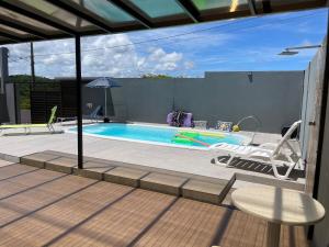 a swimming pool with two chairs and a table and an umbrella at Casa com piscina e hidromassagem in Ilhéus