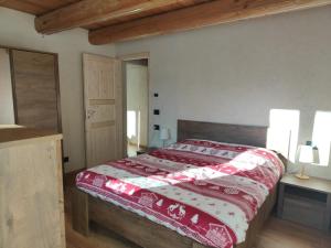 a bedroom with a bed with a red and white comforter at Alloggio Bellavista in Rore
