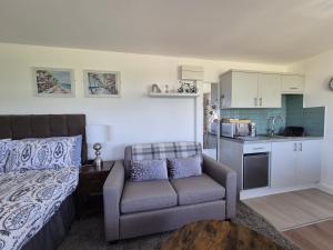 a bedroom with a couch and a chair and a kitchen at Zoila's Rest - A self-contained studio in Spalding