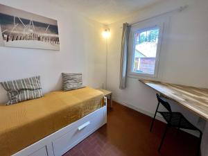 a bedroom with a bed and a desk and a window at Palombes 5 in Lacanau