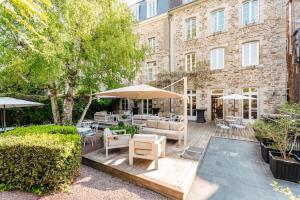 a patio with furniture and umbrellas in front of a building at Hôtel Le D'Avaugour in Dinan