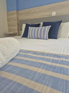 a bed with blue and white striped sheets and pillows at Proteas Mare Suites in Protaras