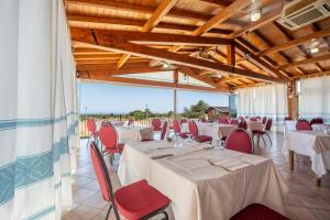 a banquet hall with white tables and red chairs at Hotel Marina in Badesi