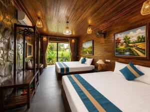a hotel room with two beds and a large window at Tam Coc Mountain Ecolodge in Ninh Binh