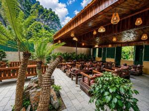 a restaurant with palm trees and wooden tables and chairs at Tam Coc Mountain Ecolodge in Ninh Binh