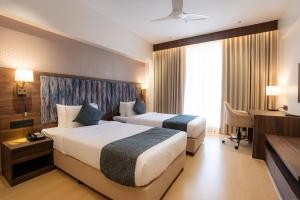 a hotel room with two beds and a desk at Akaya Elegance in Ahmadnagar