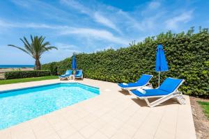a swimming pool with two chairs and umbrellas at Seafront Villa Ocean Pearl - Private Beach Area & Pool in Polis Chrysochous