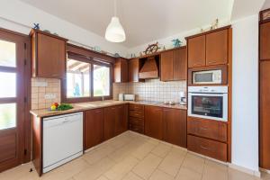 a kitchen with wooden cabinets and a white appliance at Seafront Villa Ocean Pearl - Private Beach Area & Pool in Polis Chrysochous