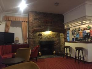 a living room with a fireplace with chairs and a table at Healey House Hotel in Batley