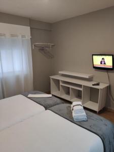 a hotel room with a bed and a tv and a tv at Ecorooms SCQ estación in Santiago de Compostela