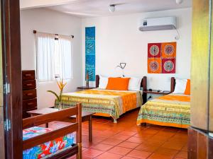 a room with two beds and a table at Pousada Casa da Edinha in Ilha de Boipeba
