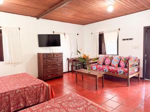 a living room with a couch and a tv at Pousada Casa da Edinha in Ilha de Boipeba