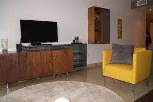 un soggiorno con TV e sedia gialla di Splendide Appartement Deluxe a Manilva