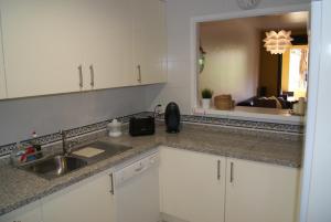 una cucina con armadi bianchi, lavandino e specchio di Splendide Appartement Deluxe a Manilva