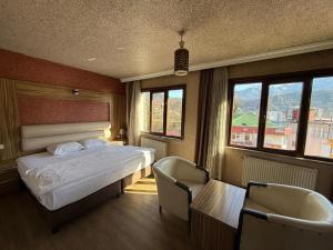 a bedroom with a bed and two chairs and windows at Otel Ustabaş in Hopa