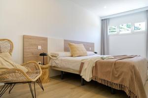 a bedroom with a bed and a chair and a window at Deva Beach Boutique Apartments in San Bartolomé