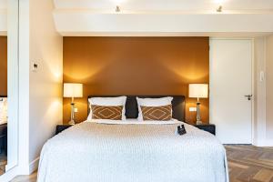 a bedroom with a large bed with two lamps at 't Ganzenest Restaurant # klein hotel in Rijswijk