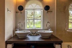 a bathroom with two sinks and a window at 't Ganzenest Restaurant # klein hotel in Rijswijk +7 photos