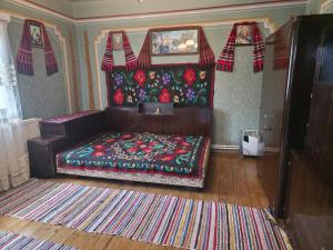 a bedroom with a bed with a colorful blanket at La Umbra Muntilor Traditional House in Ocoliş