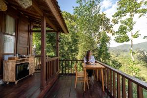 a woman sitting at a table on the deck of a cabin at Nari Swari Sidemen in Karangasem