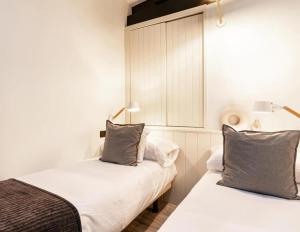two beds in a room with white walls and gray pillows at El Nido Rural Boutique Villa in La Focella