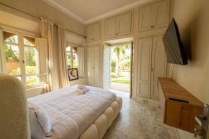 a bedroom with a white bed and a television at Villa Aurea Marrakech in Gzoula
