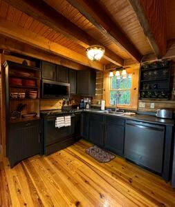 a kitchen with black cabinets and a wooden floor at Cedar Gap Hideaway in Indiana in Birdseye +7 photos